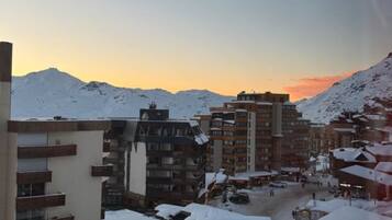 A snow-covered town with multiple buildings, including a hotel with balconies and a parking area.