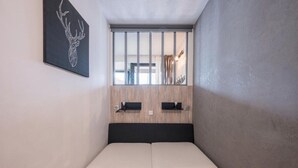 Une petite chambre moderne, dotée d’un lit, d’un mur recouvert de panneaux en bois et d’une œuvre d’art représentant une tête de cerf encadrée.