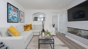 A modern living room with a white sofa, a glass coffee table, and a fireplace. - Stylish 3-Bed Retreat with Hot Tub & Garden | Near Perth City Centre (Perth)