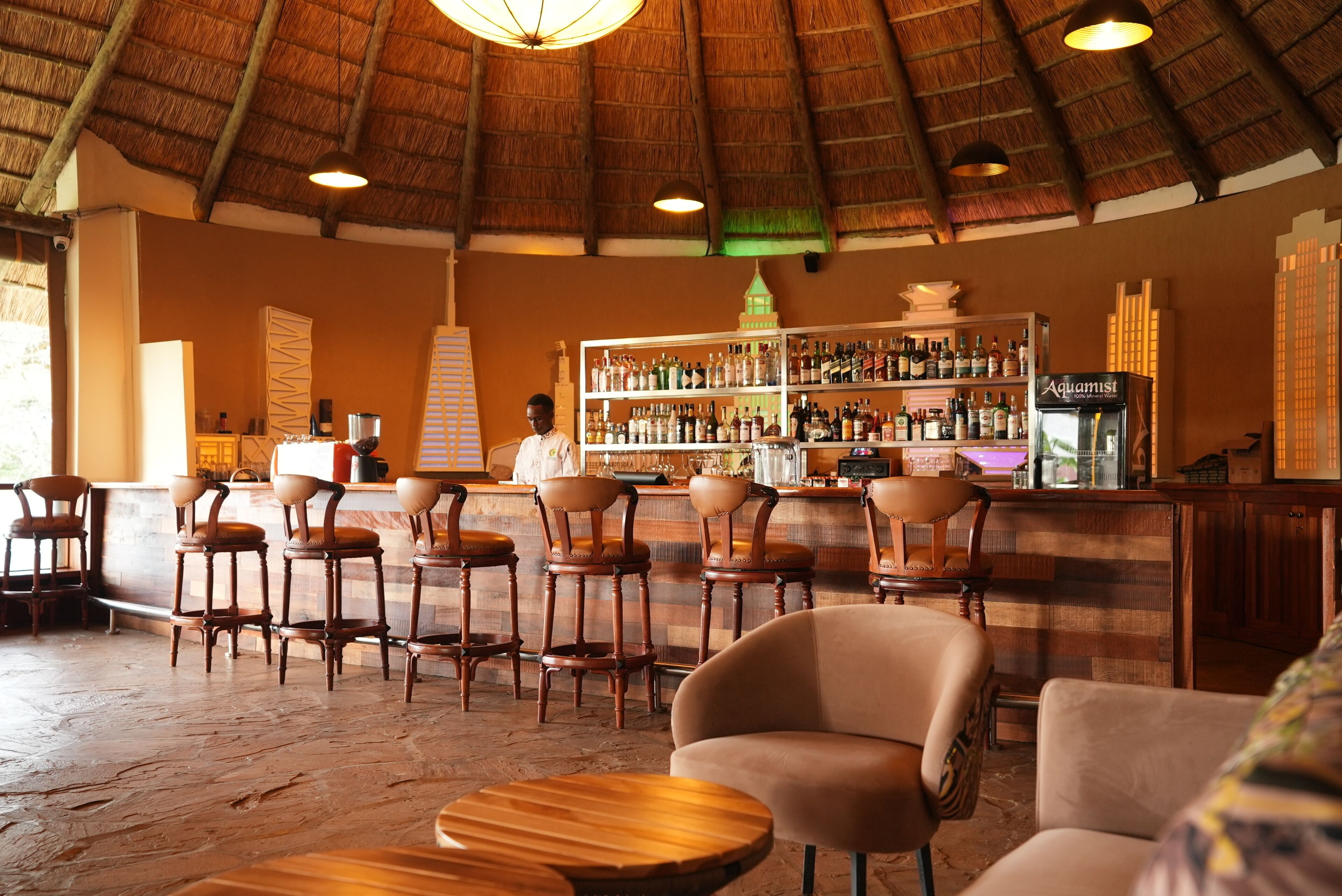 A bar area with wooden chairs and a bar counter stocked with bottles.