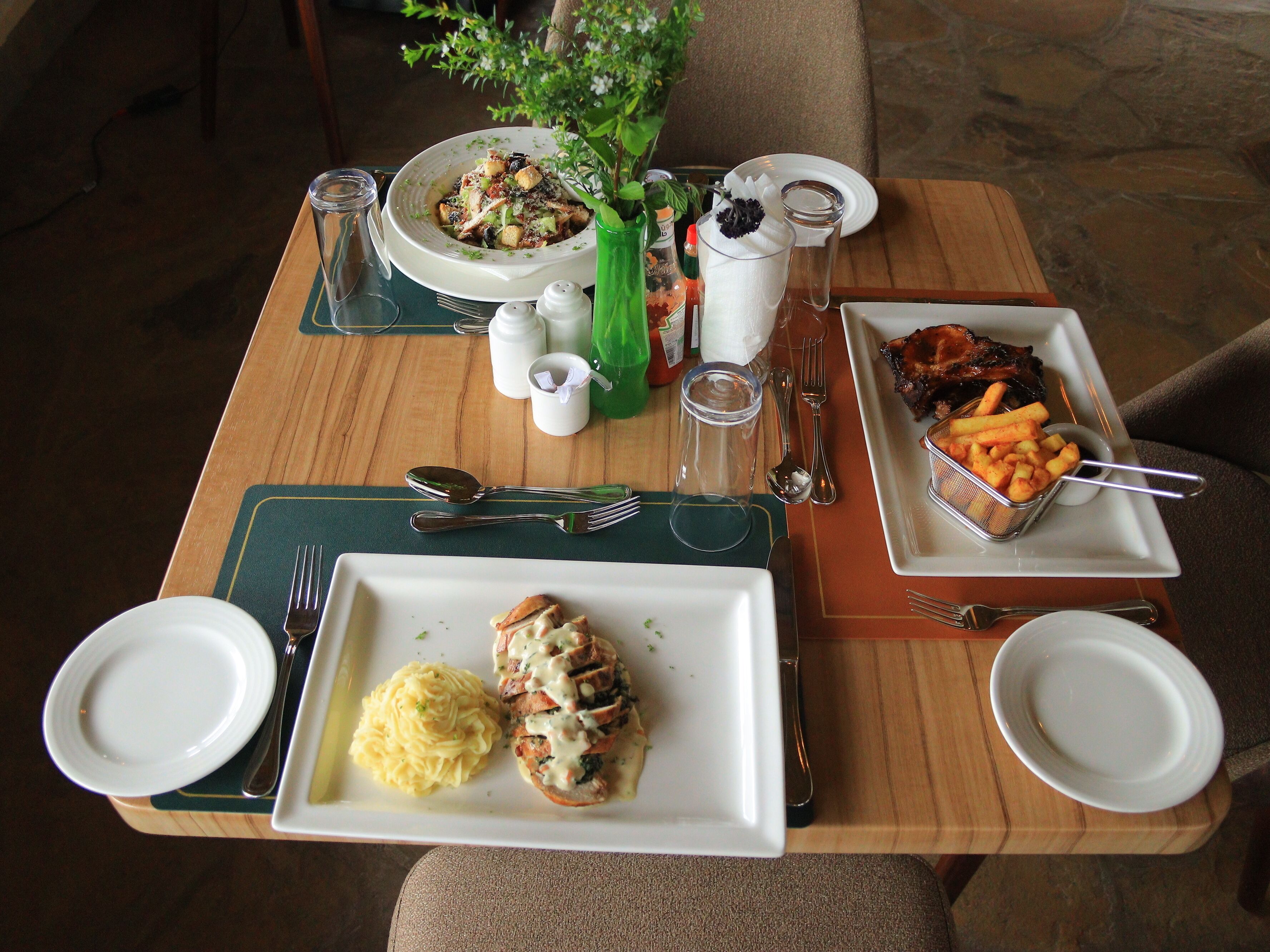 A dining table set with plates of food, cutlery, and condiments.