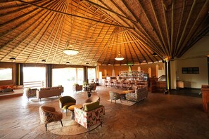 A spacious indoor area with a high thatched roof, multiple seating arrangements, and a bar area. - Esidai by Camp David (Nairobi)