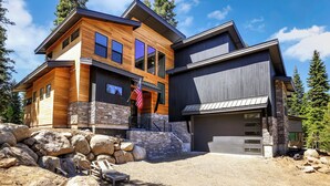 A modern two-story house with a stone foundation, large windows, and a garage. - Modern Mountain Wellness Retreat in McCall, Idaho: 4 Bed · 4.5 Bath · Sleeps 10 (McCall)