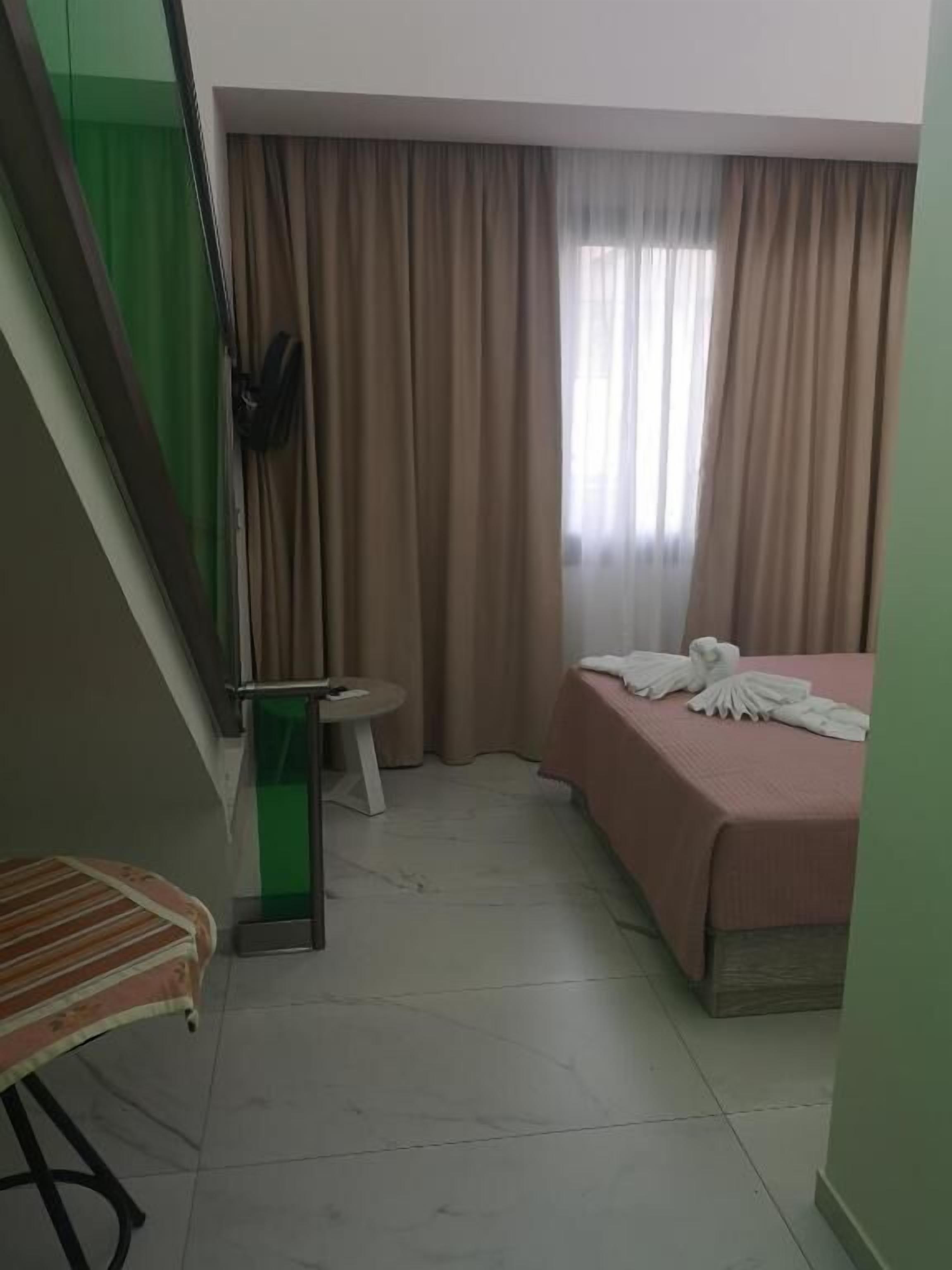 Una camera d'albergo con un letto, un tavolino rotondo, una sedia e una scala.