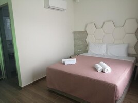 Habitación de hotel con una cama, cabecera de patrón hexagonal y aire acondicionado de pared.