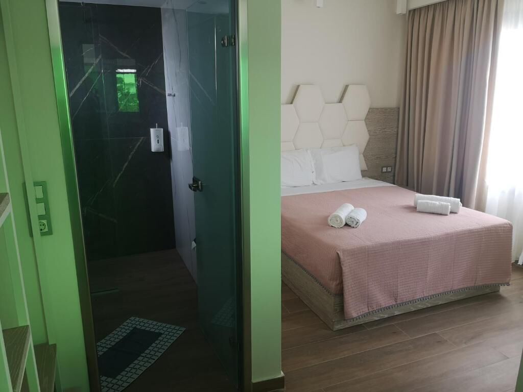 Una habitación de hotel con una cama, una puerta que da a un baño y una ventana con cortinas.