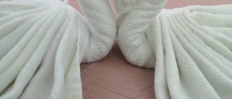 A bed with two towels arranged in the shape of swans.