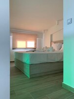 Un dormitorio con cama, ventana con persianas y suelo de madera.