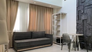 Een moderne woonkamer met een bank, een kleine tafel en een boekenkast.
