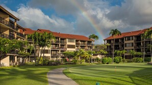Un parcours de golf avec un sentier menant à l’aire de départ, entouré d’immeubles à plusieurs étages dotés de balcons et de palmiers.