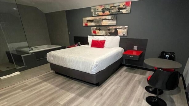 A modern bedroom with a bed, bedside tables, a desk, and a chair. - Astro Pasadena Hotel (Pasadena)
