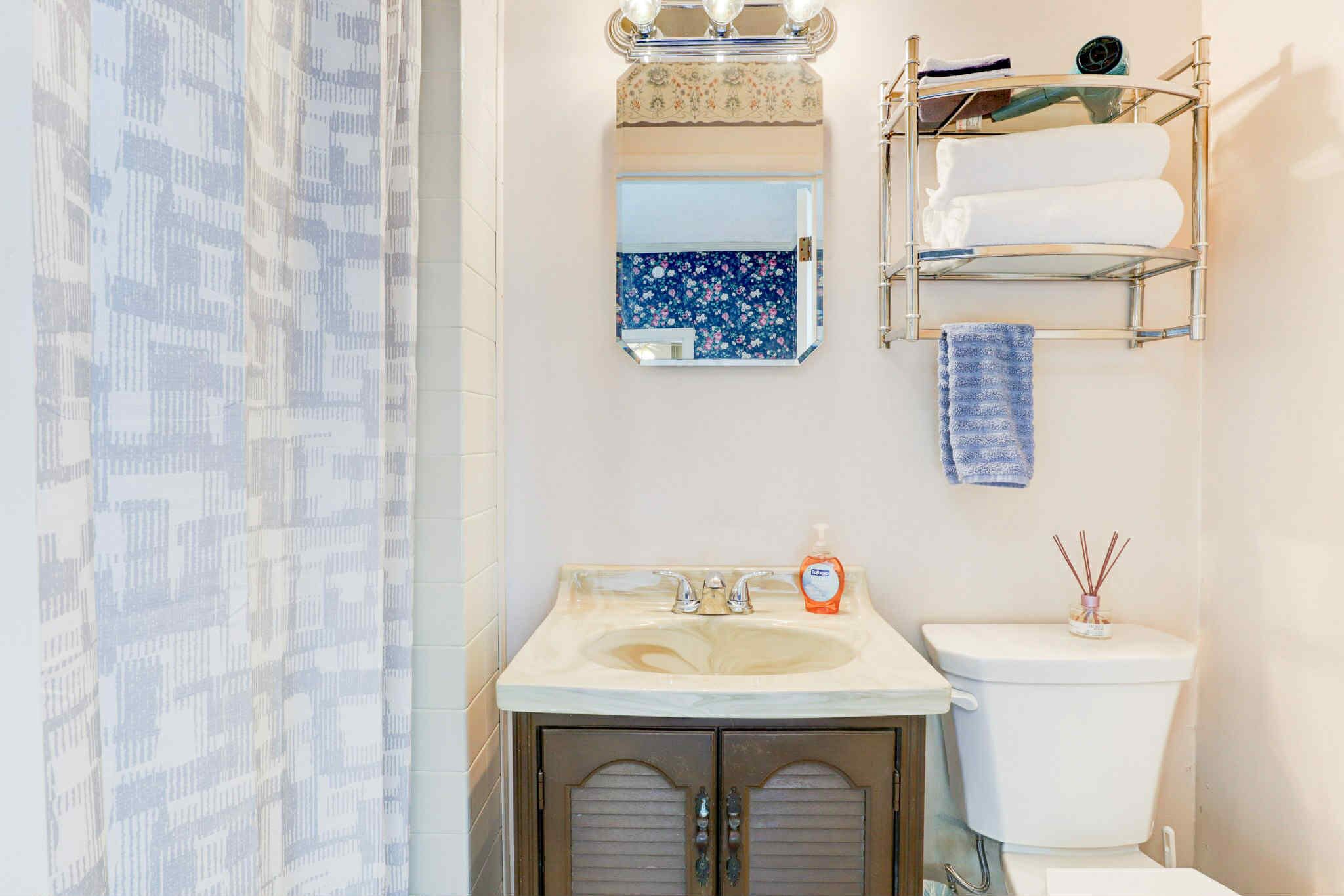 Ein Badezimmer mit Waschbecken, Spiegel, Handtuchhalter und Toilette.