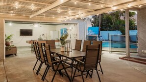 A covered outdoor dining area with a pool in the background. - Blue Haven | Solar Pool Heat + Parking + Billiards (Long Beach)