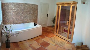 Un baño con una bañera grande, un muro de mosaico, una puerta de madera y piso de baldosas.