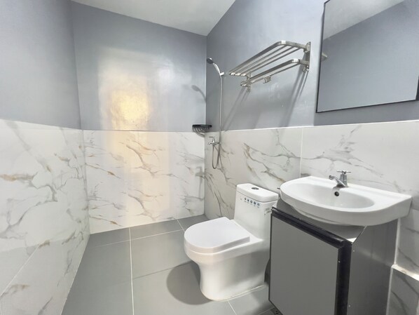 A bathroom with a toilet, sink, and shower.