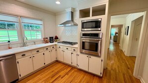 Uma cozinha moderna com armários brancos, eletrodomésticos de aço inoxidável e piso de madeira.