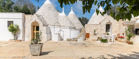 A courtyard with stone buildings, a central seating area, and potted plants.