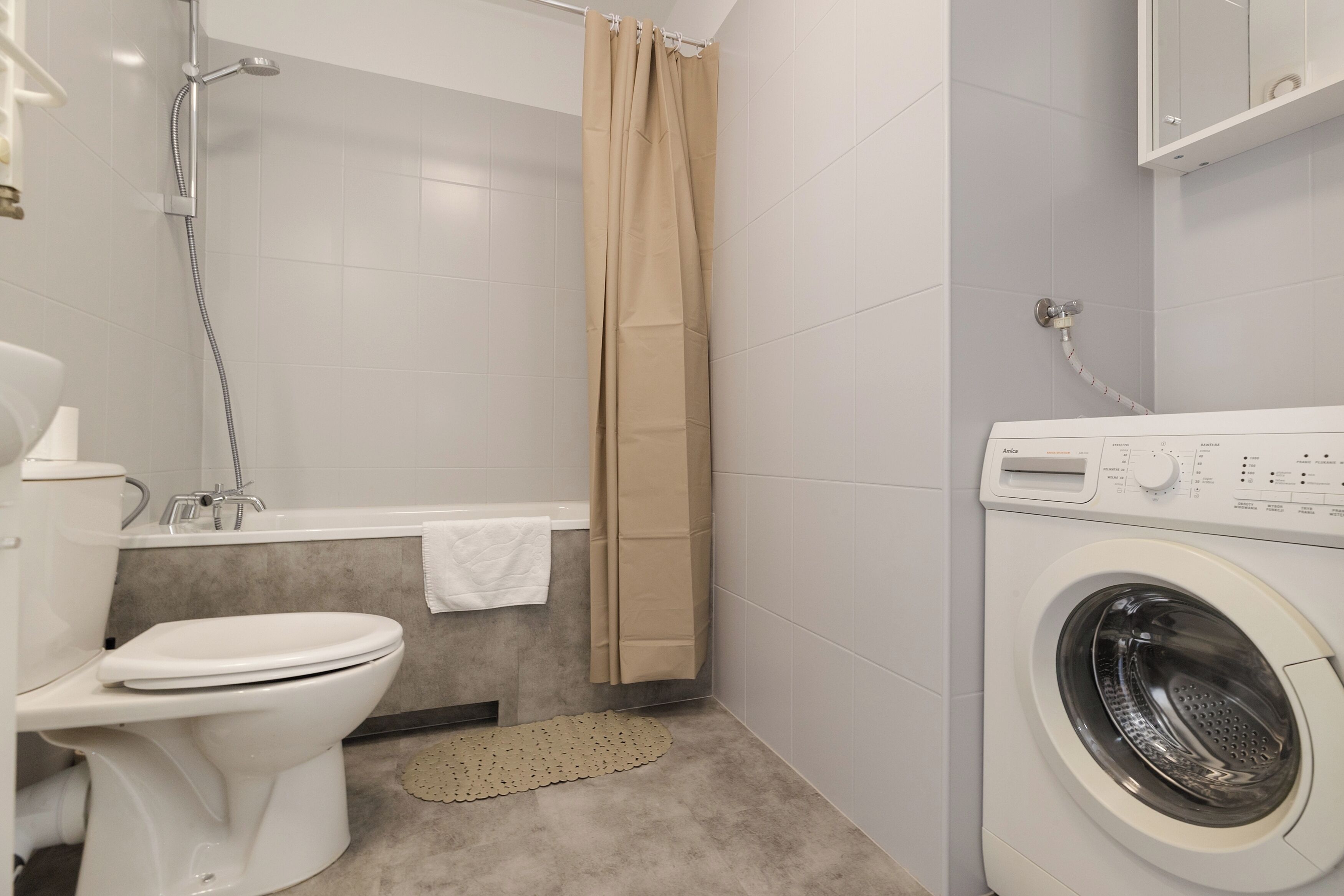 A bathroom with a toilet, shower, bathtub, and a front-loading washing machine.