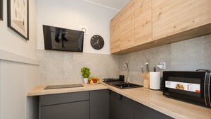 Une cuisine moderne avec un plan de travail en bois, un micro-ondes noir, un évier et une horloge au mur.