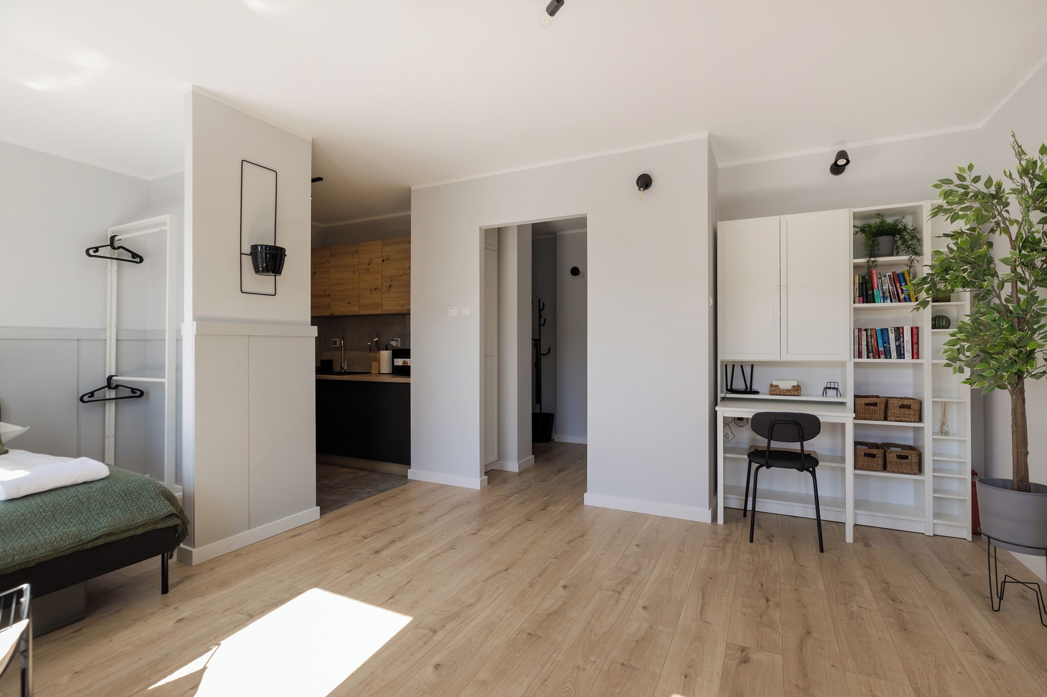 A modern, well-lit room with a bed, a desk, and a bookshelf.