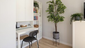 Un espace de travail avec un bureau blanc, une chaise noire et une bibliothèque remplie de livres et d’objets décoratifs.