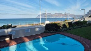 A swimming pool with a view of the ocean and mountains in the background. - Kalk Bay Secure Seaside Apartment (Cape Town)