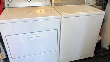 Eine weiße, übereinander gestellte Waschmaschine und Trockner mit Bedienelementen und einer Fronttür.