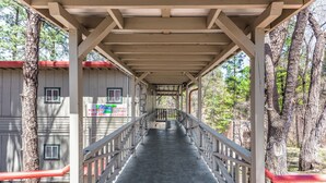 Une passerelle couverte, dotée d’une rambarde métallique, relie deux bâtiments équipés de fenêtres.