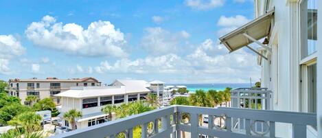 A balcony with a view of a coastal area, including buildings and a road with cars.