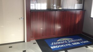 A reception area with a wooden panel wall, a door, and a blue mat with "Howard Johnson Brooklyn, New York" text. - Rockaway Hotel Brooklyn (Brooklyn)