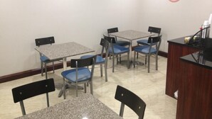 A conference room with tables and chairs, a TV mounted on the wall, and a logo on the wall. - Rockaway Hotel Brooklyn (Brooklyn)
