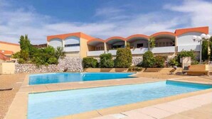Un hôtel doté d’une piscine, de plusieurs balcons et d’un mur en pierre.
