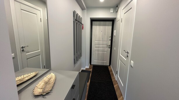 Un pasillo con alfombra negra, puertas blancas y una hoja decorativa sobre un mostrador.