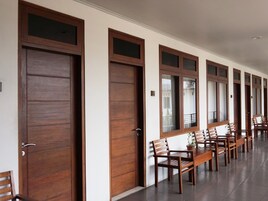 A hallway with wooden doors and windows, wooden benches, and a tiled floor.