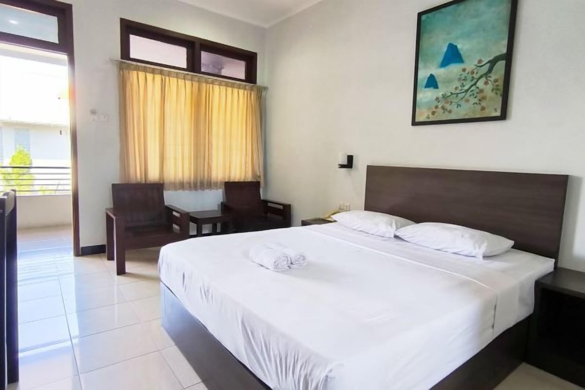 A hotel room with a large bed, a desk, and a chair.
