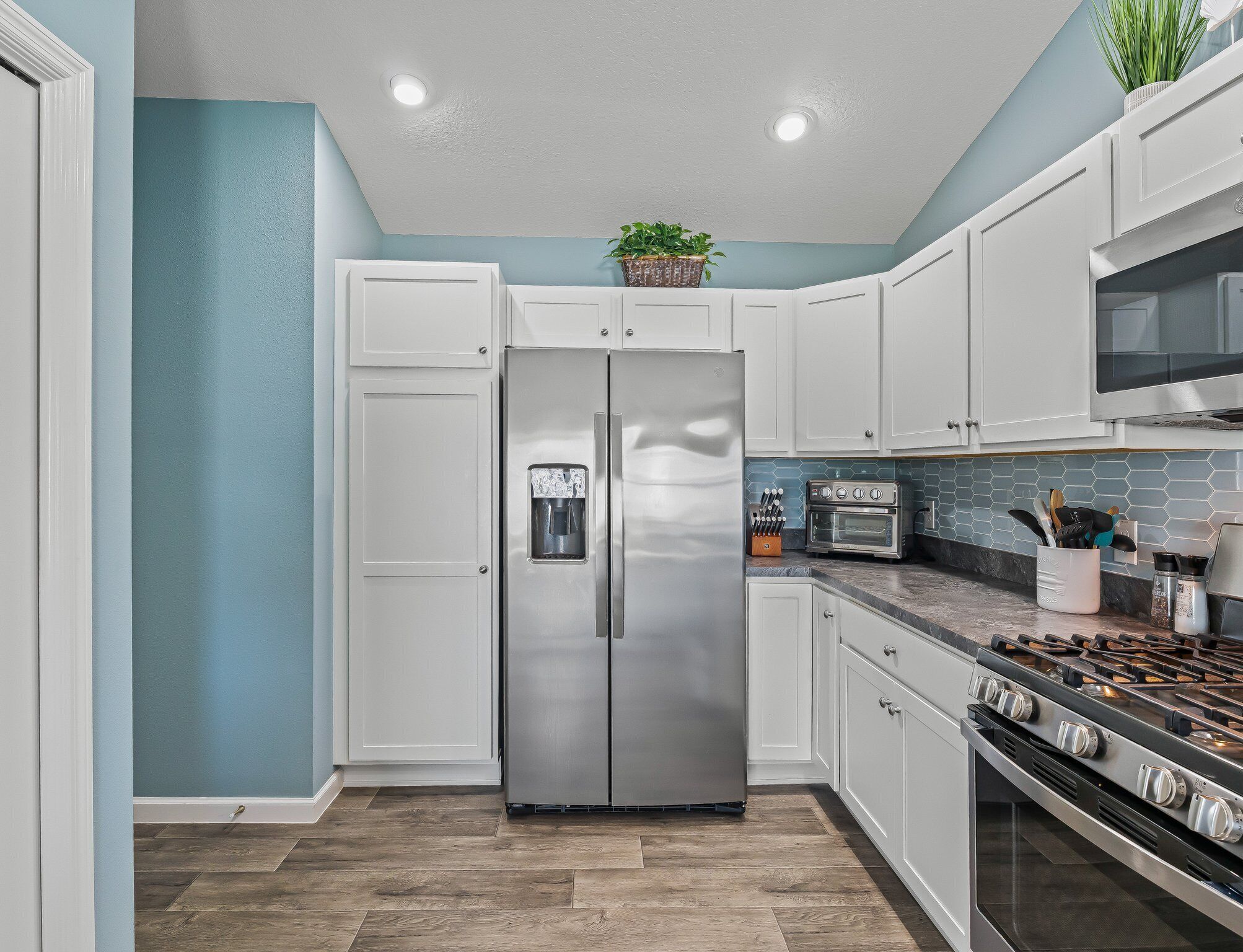 A kitchen with white cabinets, a stainless steel refrigerator, a built-in oven, and a gas range.