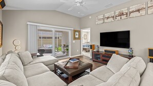 Ein geräumiges Wohnzimmer mit einer großen Couch, einem Couchtisch, einem Fernseher und Bildern an der Wand.