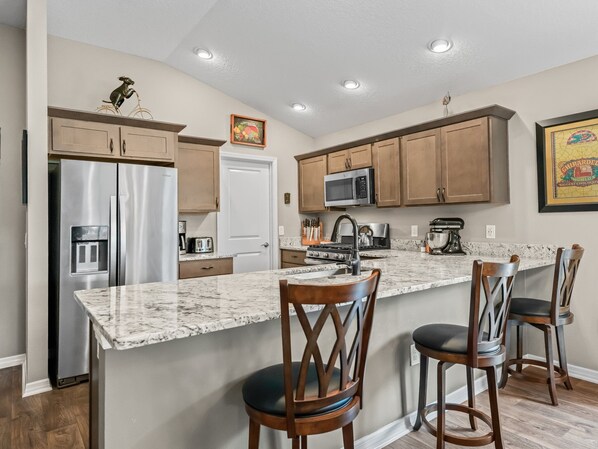 A modern kitchen with stainless steel appliances, wooden cabinets, and a marble countertop.