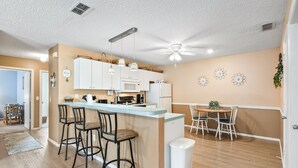 Une cuisine moderne dotée d’un îlot central, de tabourets de bar et d’un ventilateur de plafond.