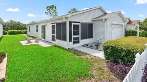 Une maison mobile de plain-pied dotée d’un patio couvert, d’une cour clôturée et d’une pelouse bien entretenue.