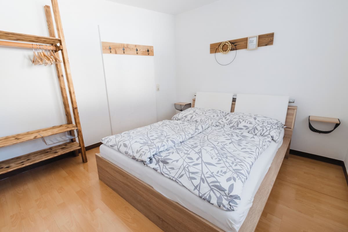 Una camera da letto con un letto con struttura in legno, un materasso bianco e un armadio in legno.