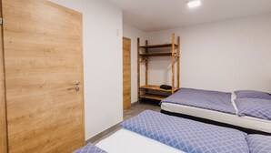 Une chambre avec deux lits, une armoire en bois et un lit superposé.