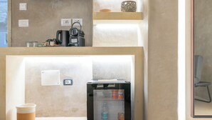 A kitchenette with a coffee maker, kettle, and a mini-fridge containing a bottle and a can. - Via Cota 24 (Lecce)
