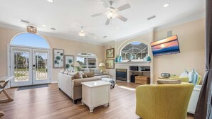 A spacious living room with hardwood flooring, a large sofa, a yellow armchair, and a fireplace. - Private Beach & Community Pool (Miramar Beach)