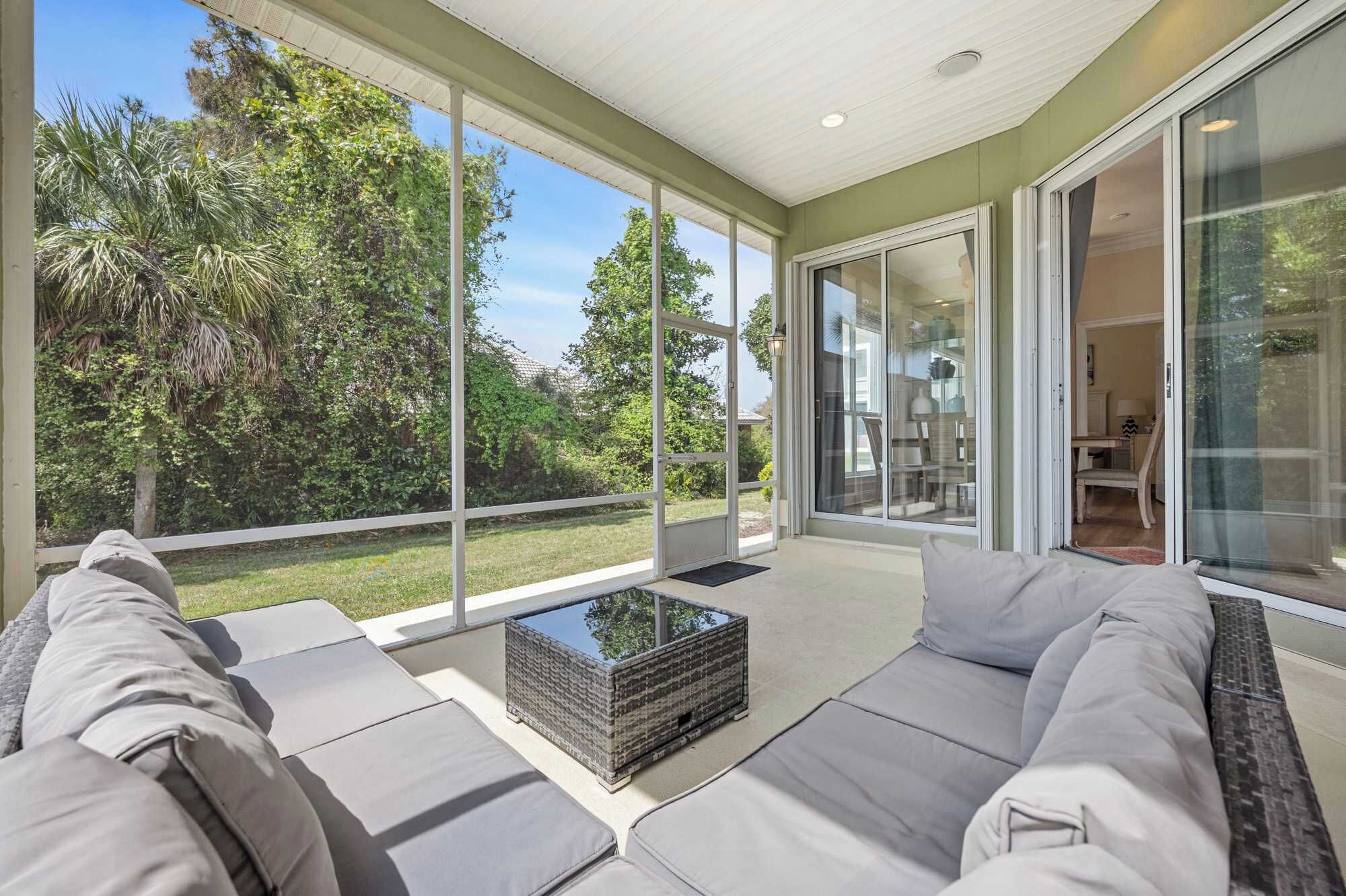 A modern living room with a large glass door leading to a patio, a sofa set, and a coffee table.