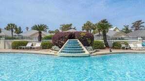 A swimming pool with a set of stairs leading into it, surrounded by lounge chairs and palm trees. - Private Beach & Community Pool (Miramar Beach)