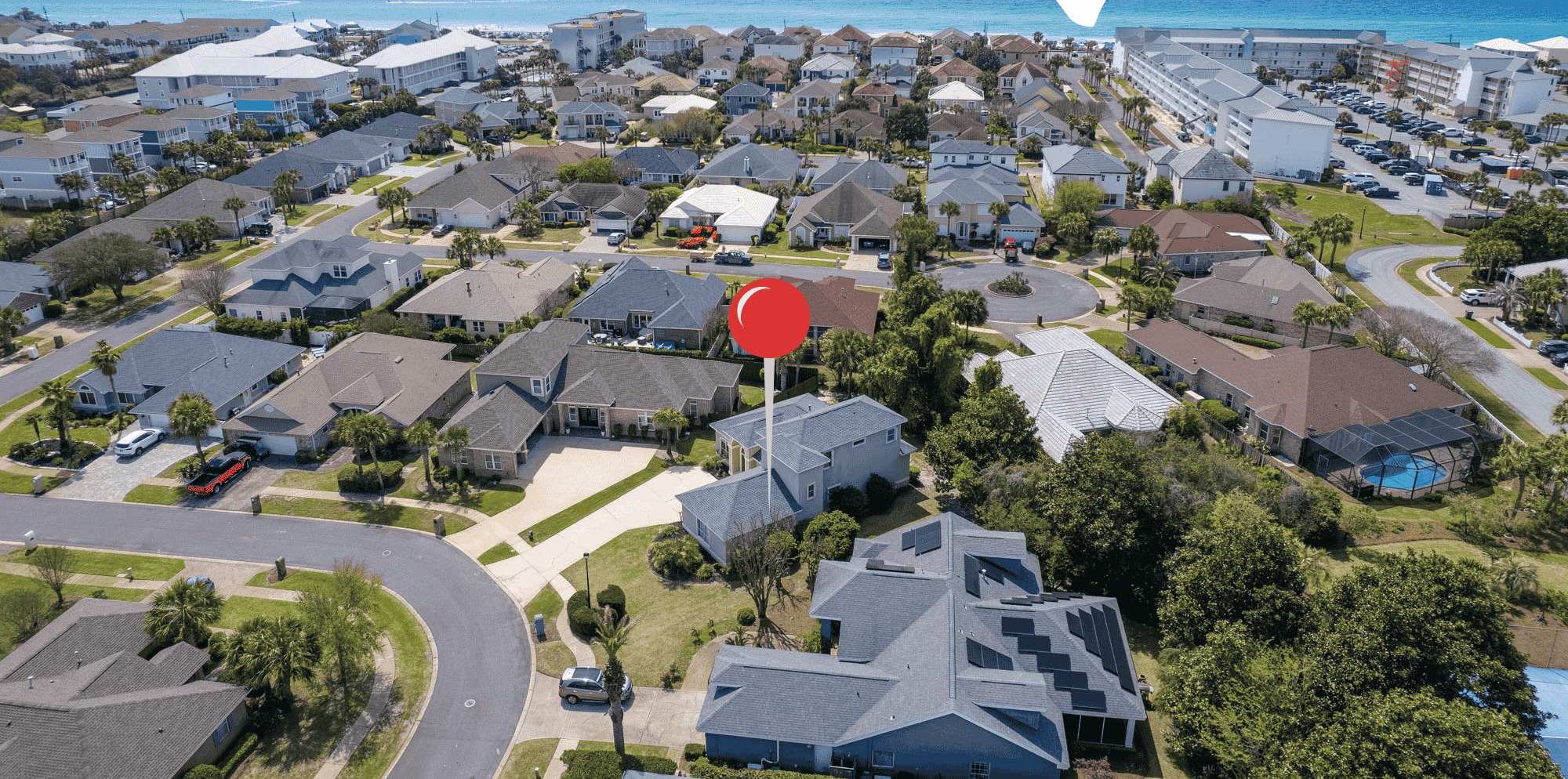 Un quartier résidentiel avec des maisons et un panneau indiquant l’accès à la plage, pointant en direction de l’océan.