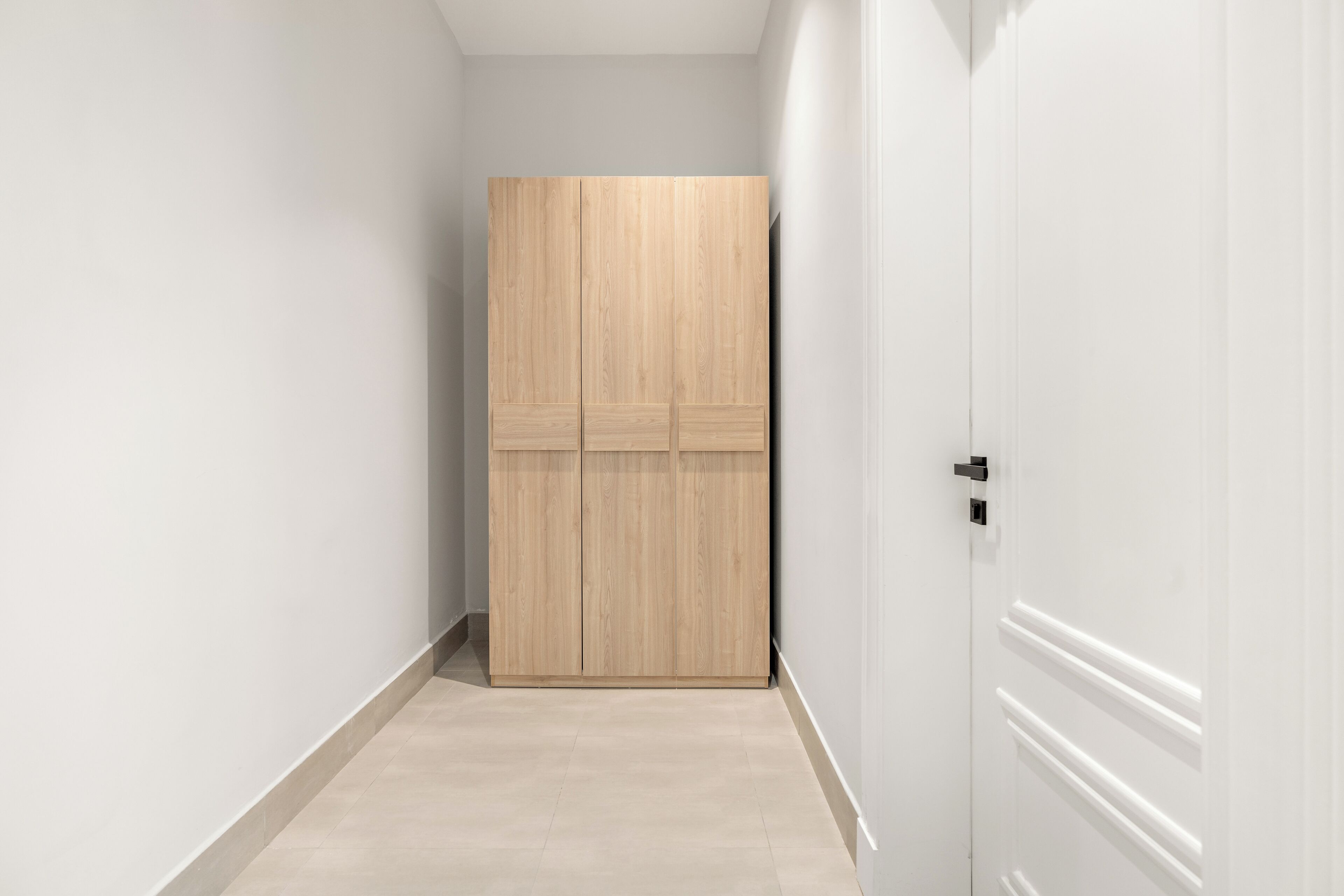 A hallway with a wooden wardrobe and a white door.