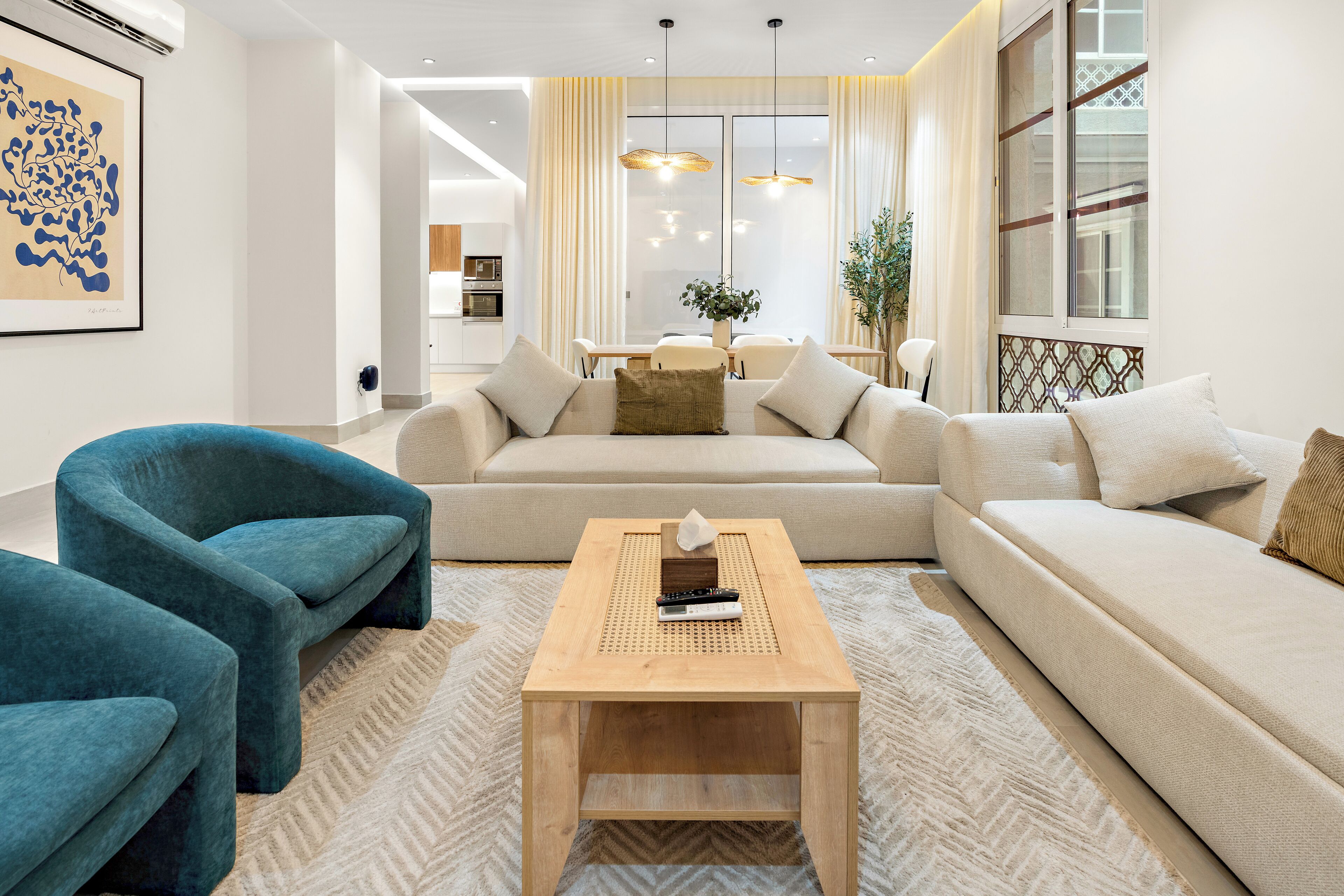 A modern living room with a sofa, two armchairs, a coffee table, and a dining area in the background.