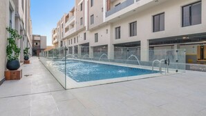 A modern building with a swimming pool, potted plants, and a clear sky. - Silkhaus Majidia 120 (Riyadh)
